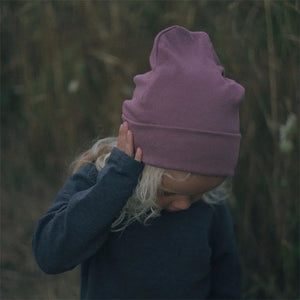 Lifestyle pic of child wearing rose coloured ribbed knit beanie hat.