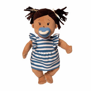 Plush Baby Stella Beige doll with brown pigtails wearing a blue and white striped dress. Blue magnetic pacifier is attached to doll, as if she is using it. Doll is 15 inches and is standing.