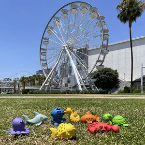 Lifestyle pic of Water Pals bath toys on grass with ferris wheel in background.
