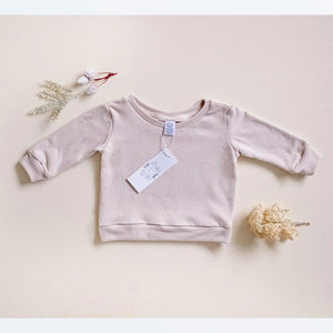 Infant and kids pullover in Oat with cuffs, waistband and seam binding at neck opening for comfort. Tag at beck of neckline.