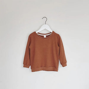 Rust colored infant and kids pullover with cuffs, waistband and seam binding at neck opening for comfort. Tag at beck of neckline.
