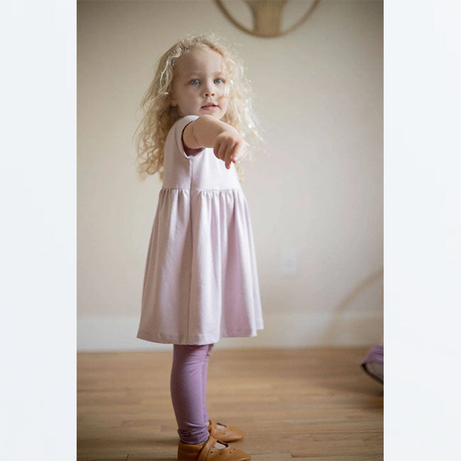 Lifestyle pic of toddler girl wearing blush pink empire waisted peplum casual dress