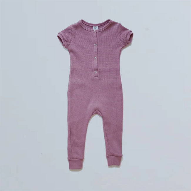 infants short sleeve long leg romper with cuff binding at sleeves and neck. The colour name is Ginger, but it is more of a dusty rose colour. Four snap buttons down front of henley-style top.