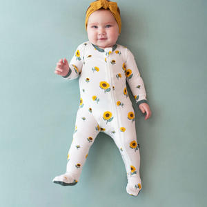 A lifestyle pic of baby wearing a zippered footie in the Sunflower print.