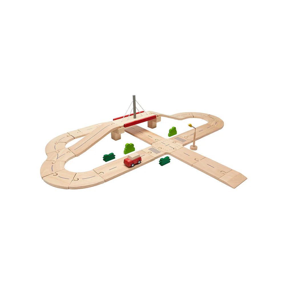 Wooden toy road track set with a red car and green trees on a white background