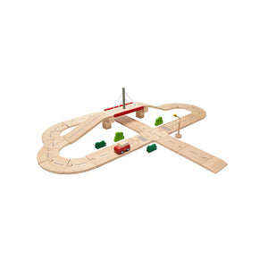 Wooden toy road track set with a red car and green trees on a white background