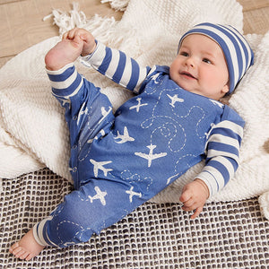 Lifestyle pic of baby wearing blue long sleeved romper with striped arms and white airplanes on body. Matching blue and white striped hat.