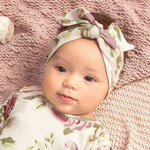 Lifestyle pic of baby wearing stretchy cotton cabbage rose print headband and matching romper